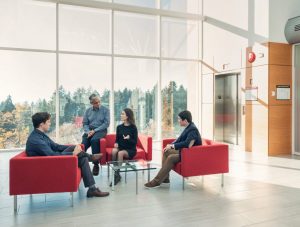 UBC MPPGA graduate students having a group discussion in a modern, common space at the Vancouver campus.